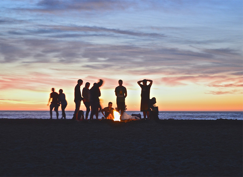 Group of people near campfire during sunset
