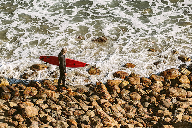 Man holding surfboard looking at the board